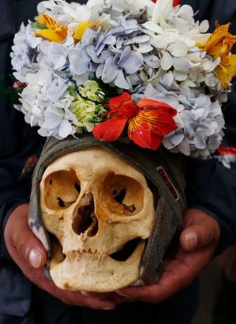 A woman carries decorated human skull or "natitas", as she waits to be greeted by the priest inside the Cementerio General chapel, during the Natitas Festival celebrations, in La Paz, Bolivia, Sunday, Nov. 8, 2015. Although some natitas have been handed down through generations, many are from unnamed, abandoned graves that are cared for and decorated by faithful. They use them as amulets believing they serve as protection. The tradition marks the end of the Catholic All Saints holiday, but is not recognized by the Catholic church. (AP Photo/Juan Karita) ORG XMIT: XJK109